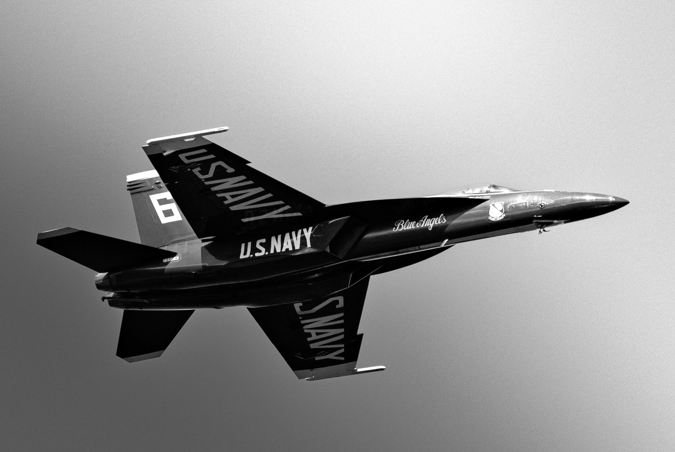 Blue Angels jet banking through a bright sky in black and white