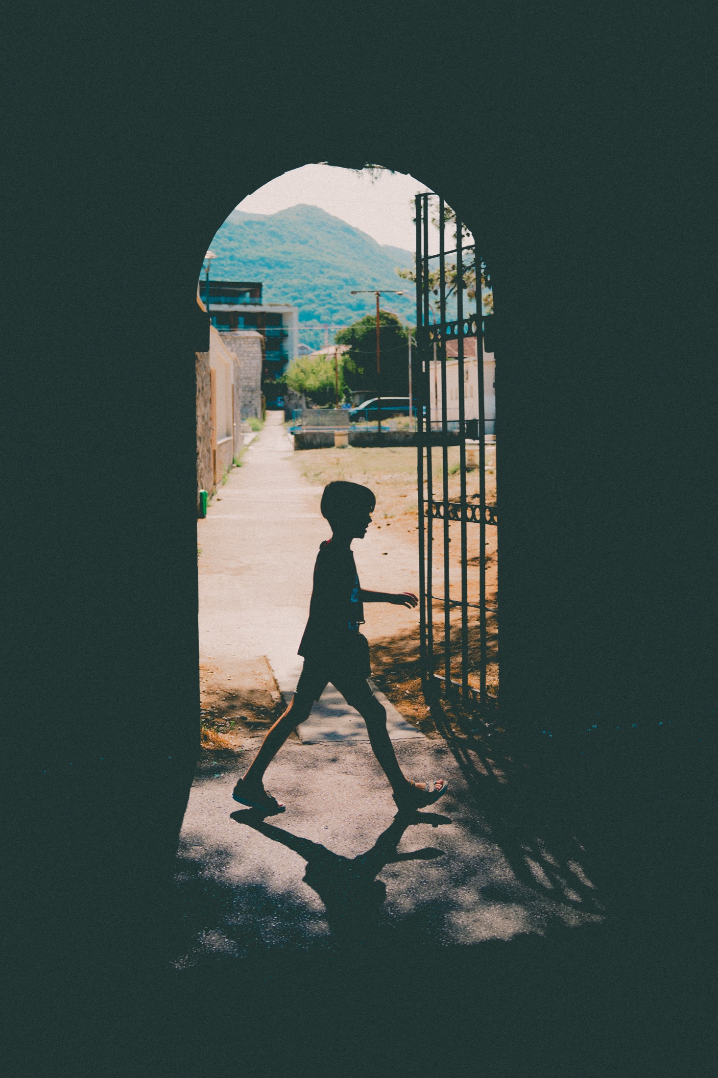 Silhouette of a child crossing through a sunlit arched gateway