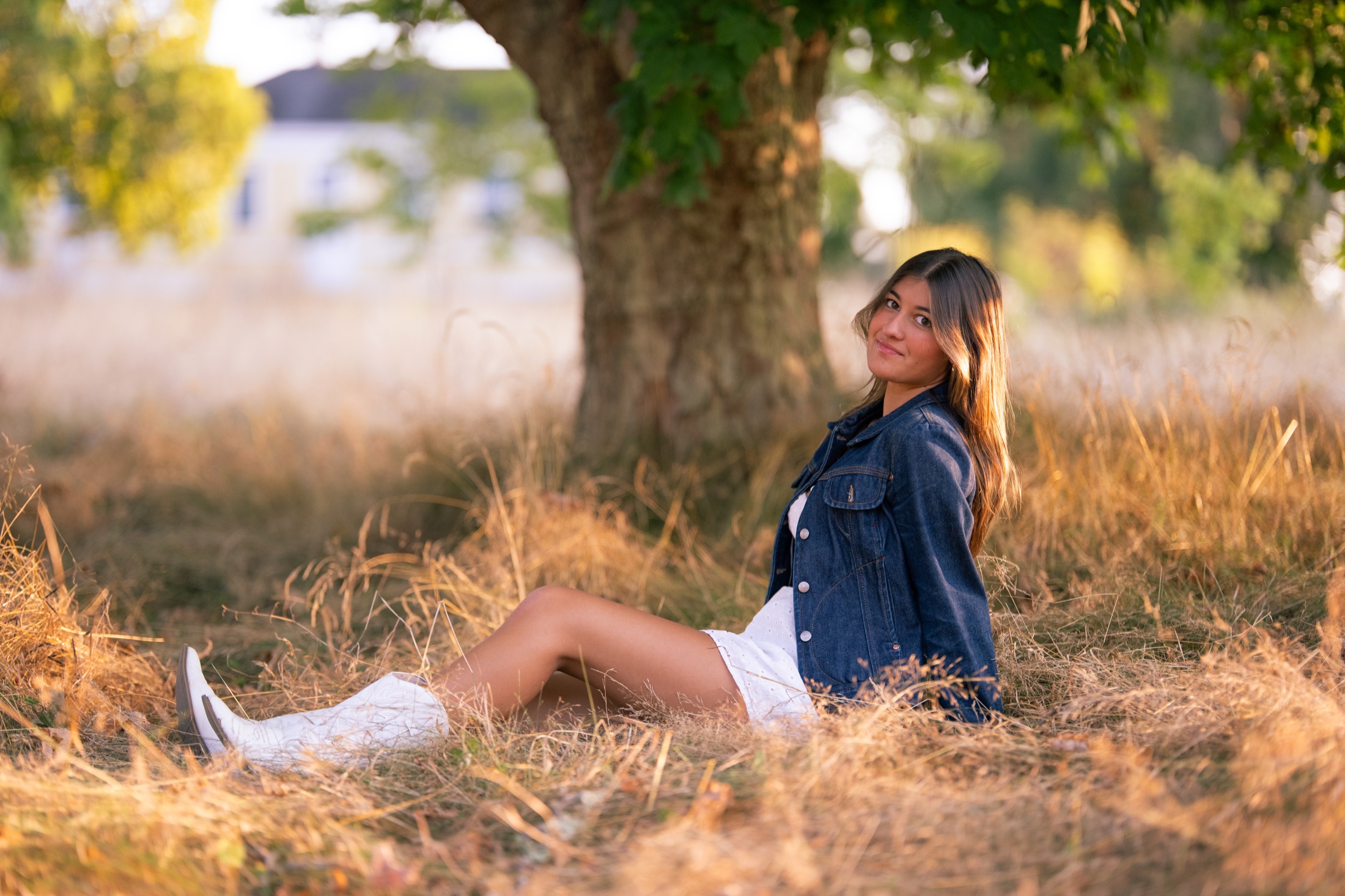 Young woman seated beneath a tree in golden evening light