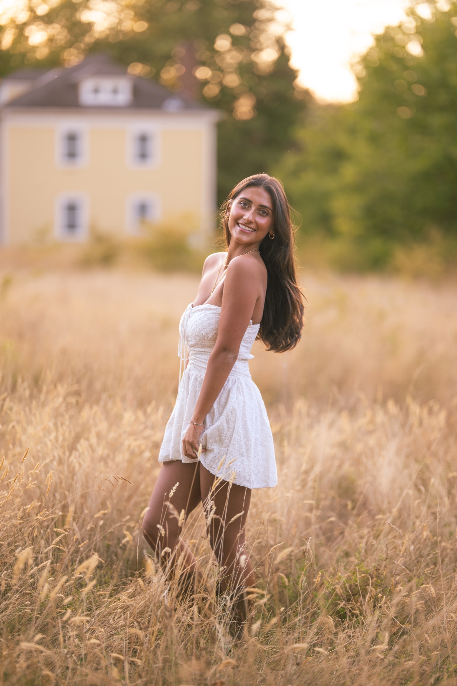 Young woman in a white dress standing in a sunlit field
