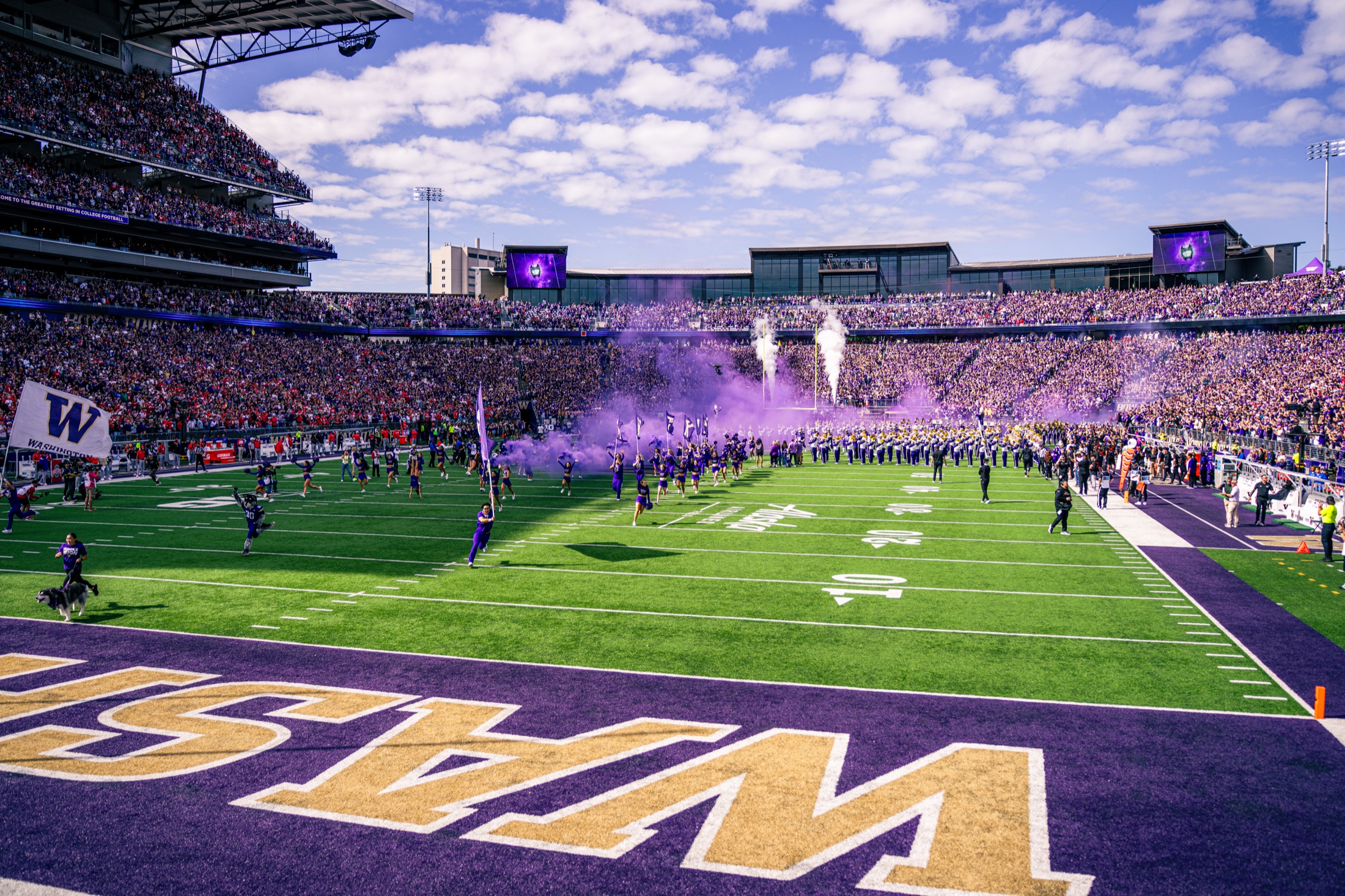 Washington football entrance with smoke, band, crowd, and team at Husky Stadium