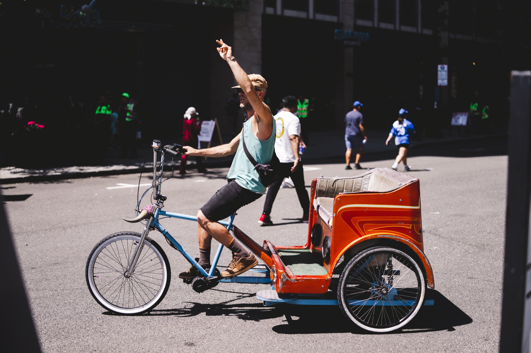 Pedicab rider gesturing while stopped on a sunny Seattle street