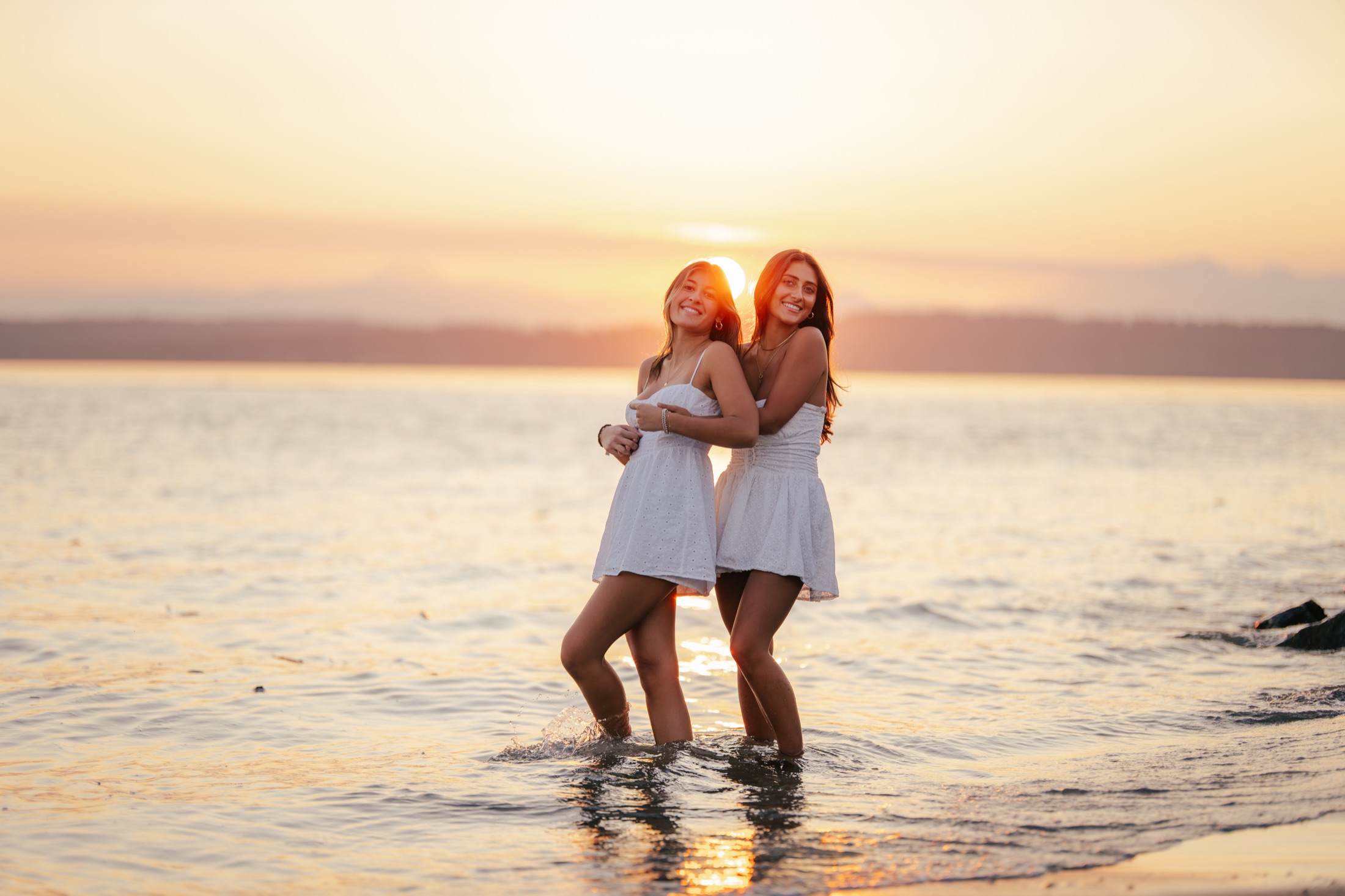 Two friends embracing in the water at golden hour