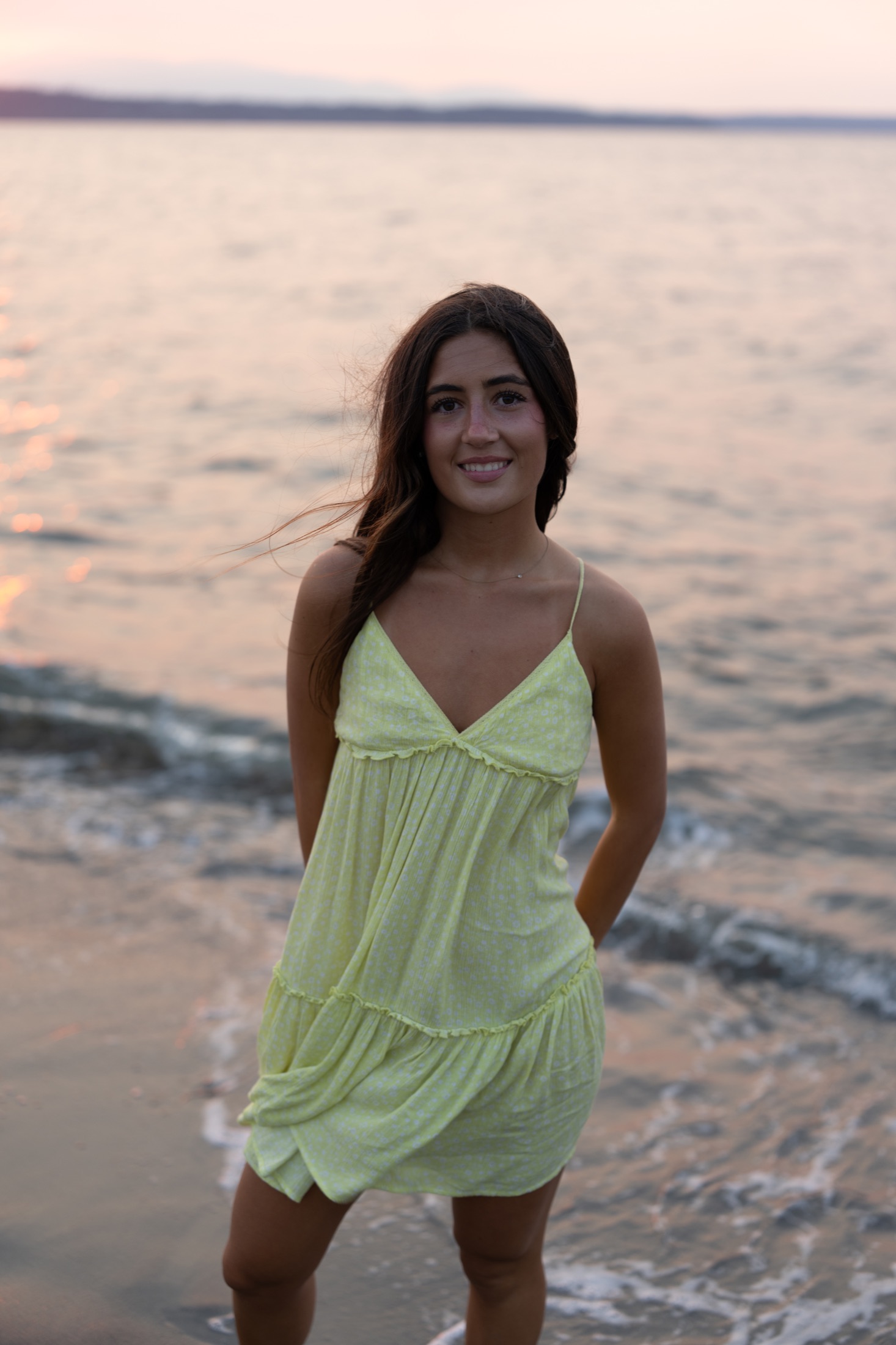 Young woman in a yellow dress standing at the edge of the water