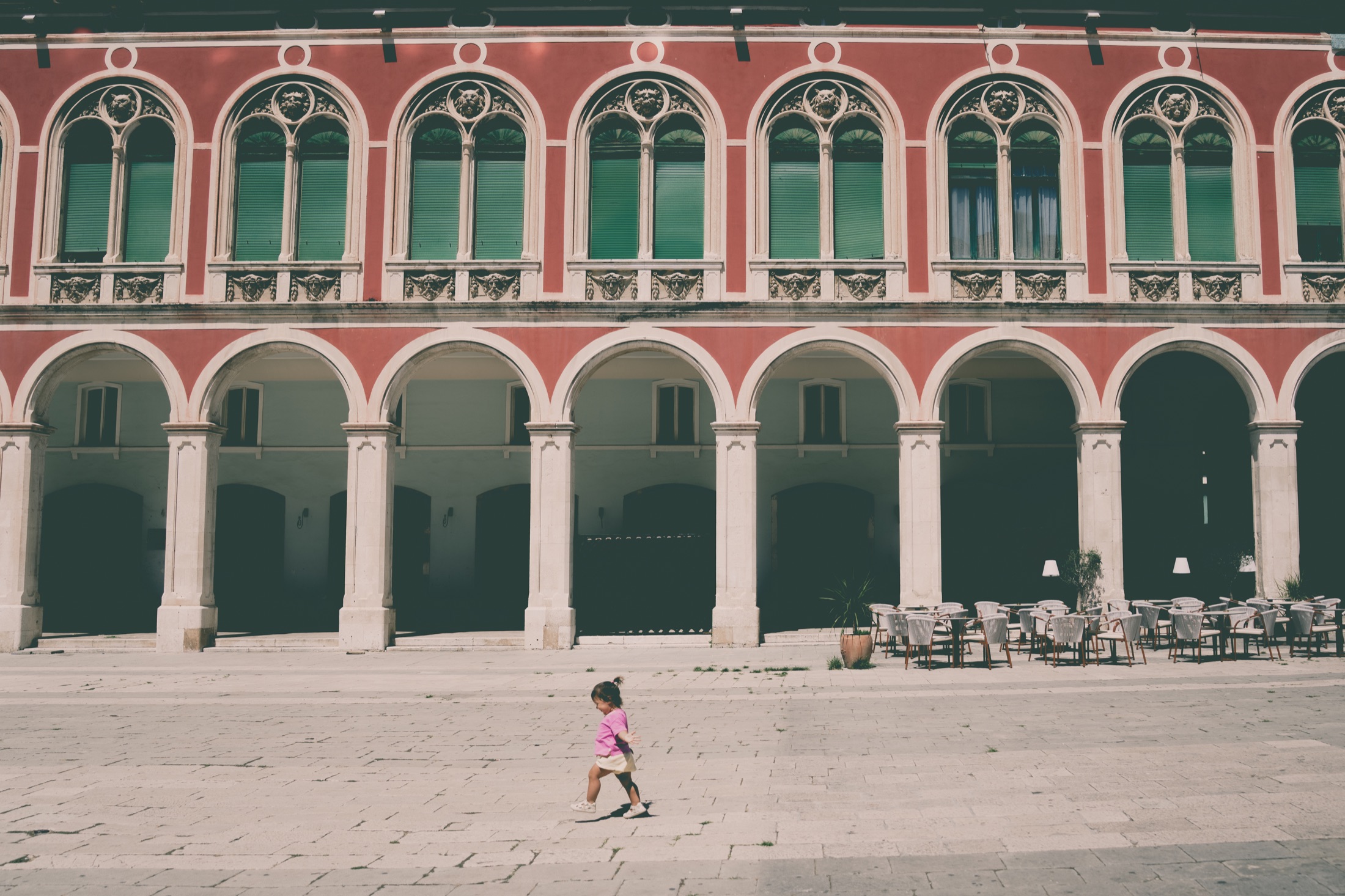A child walking across a quiet arched courtyard