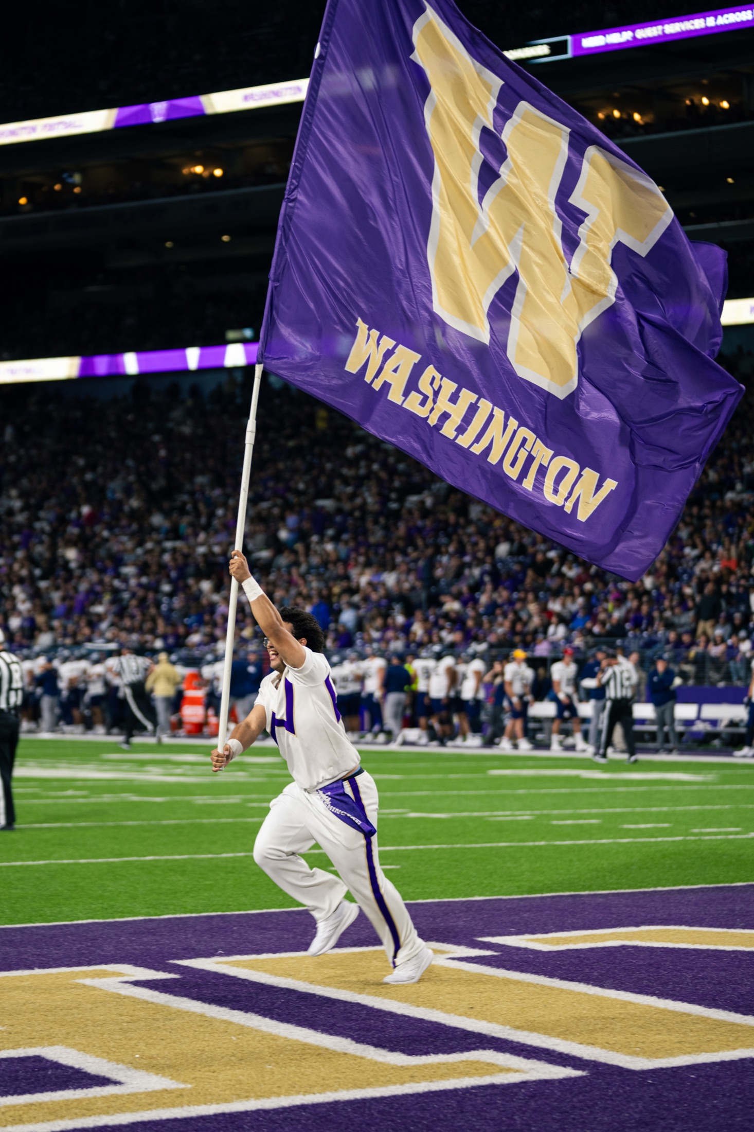 Washington flag runner carrying a large purple flag through the end zone