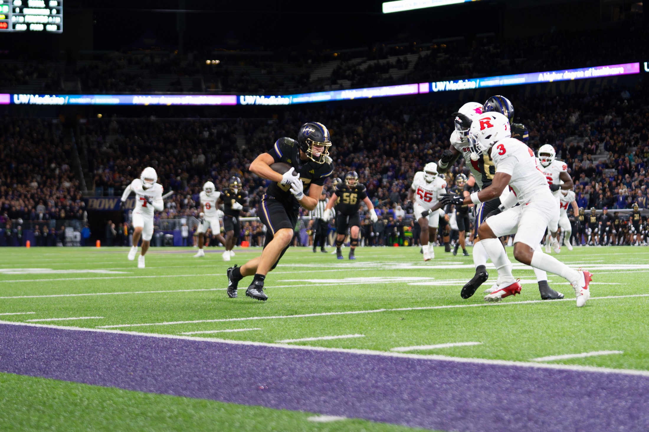 Washington ball carrier turning toward the end zone against Rutgers defenders