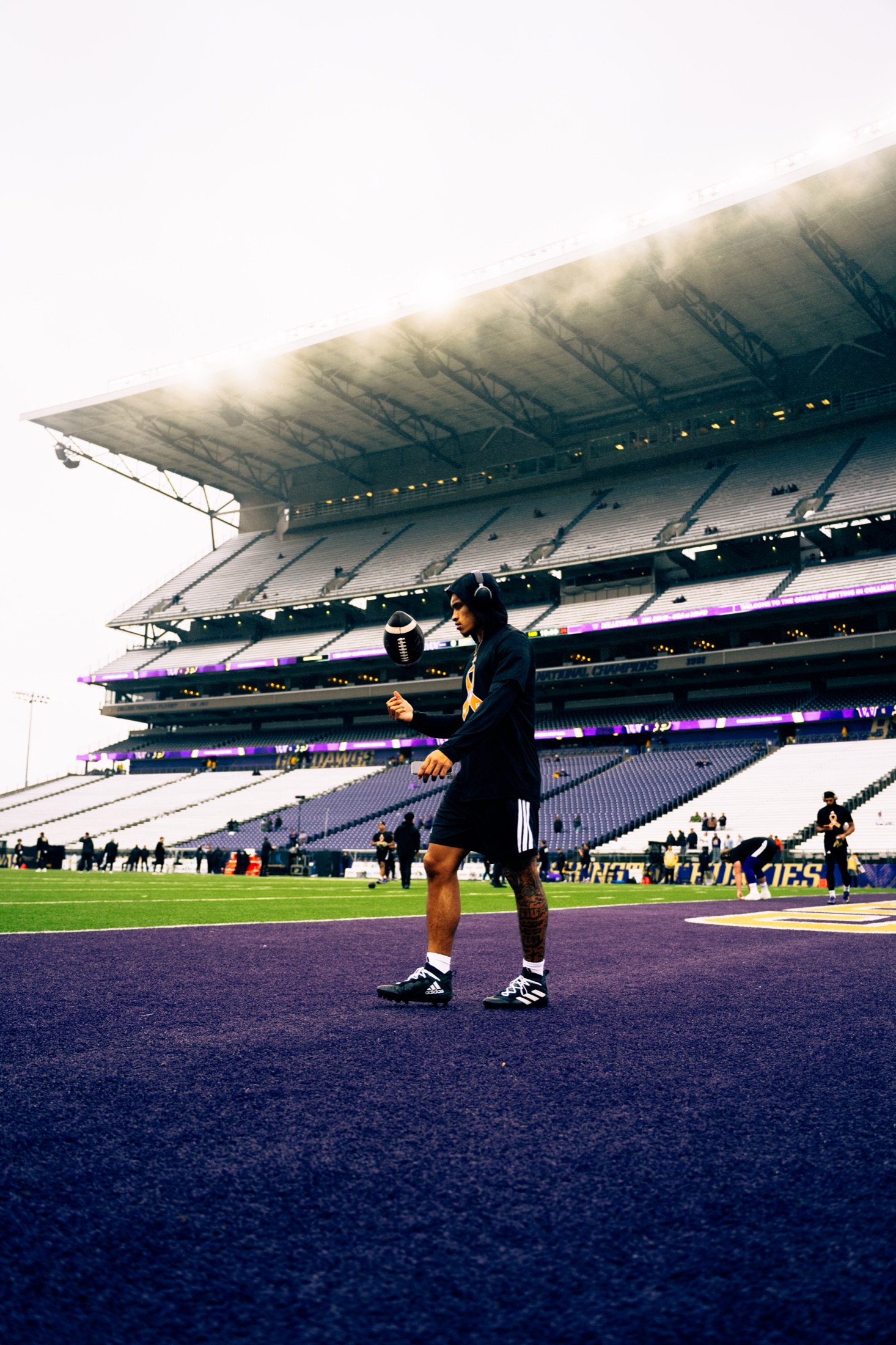 Washington player balancing a football during pregame at an empty Husky Stadium