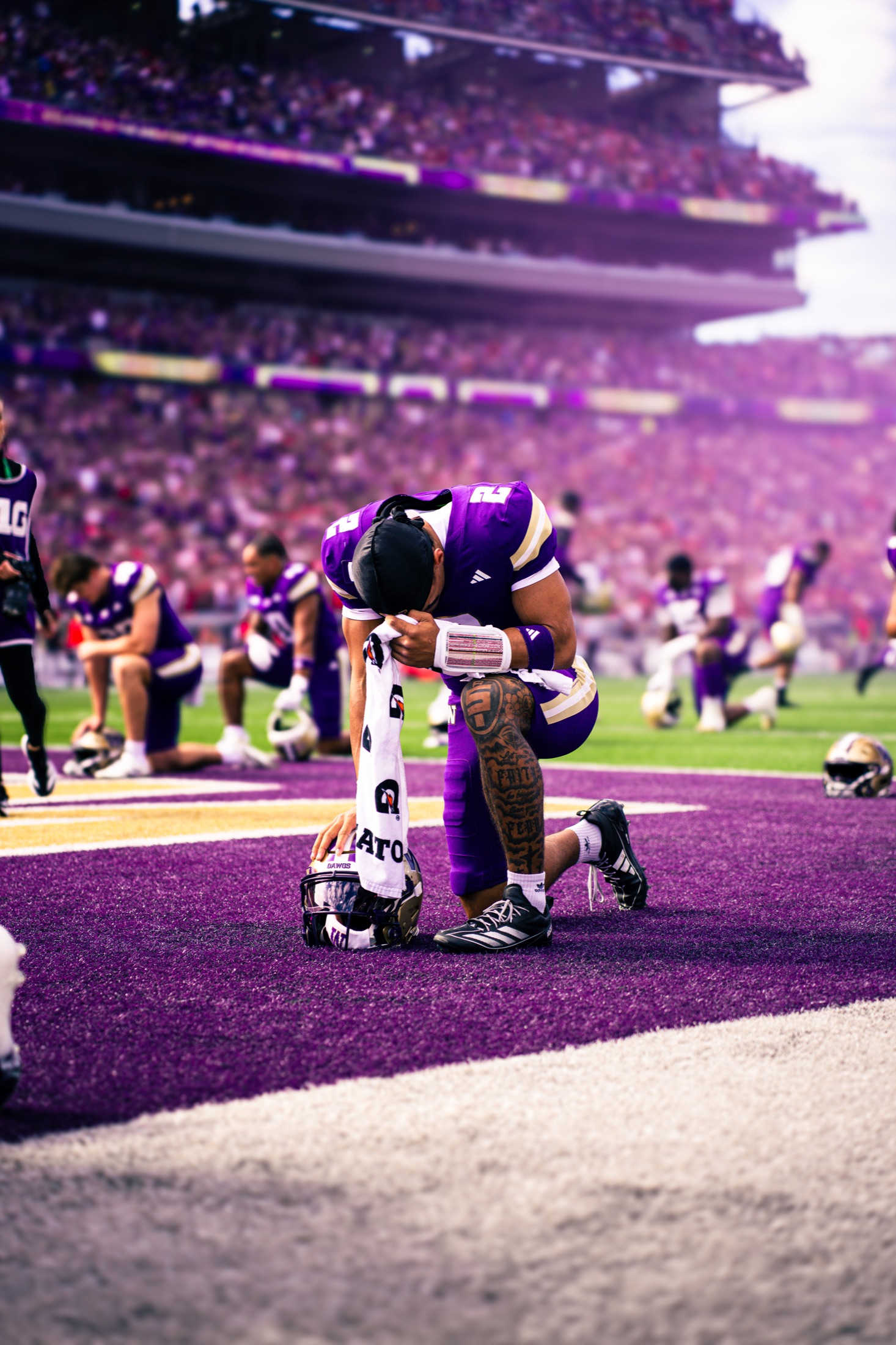 Washington quarterback kneeling on the purple turf before kickoff